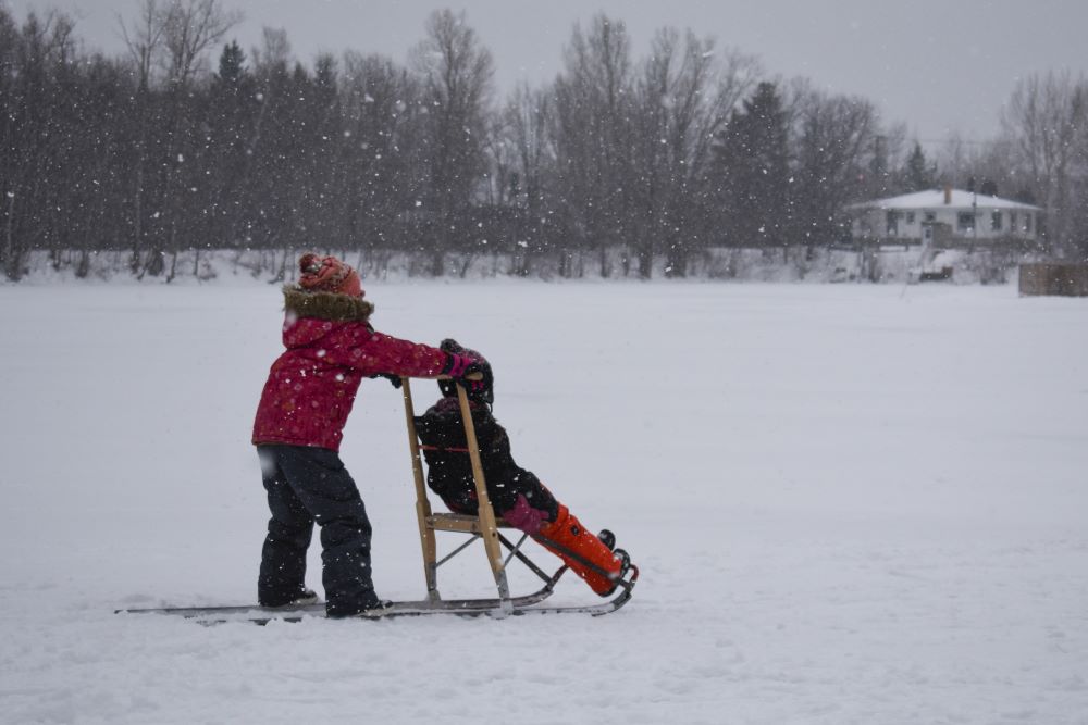 Deux enfant jouant à une trottinette de neige
